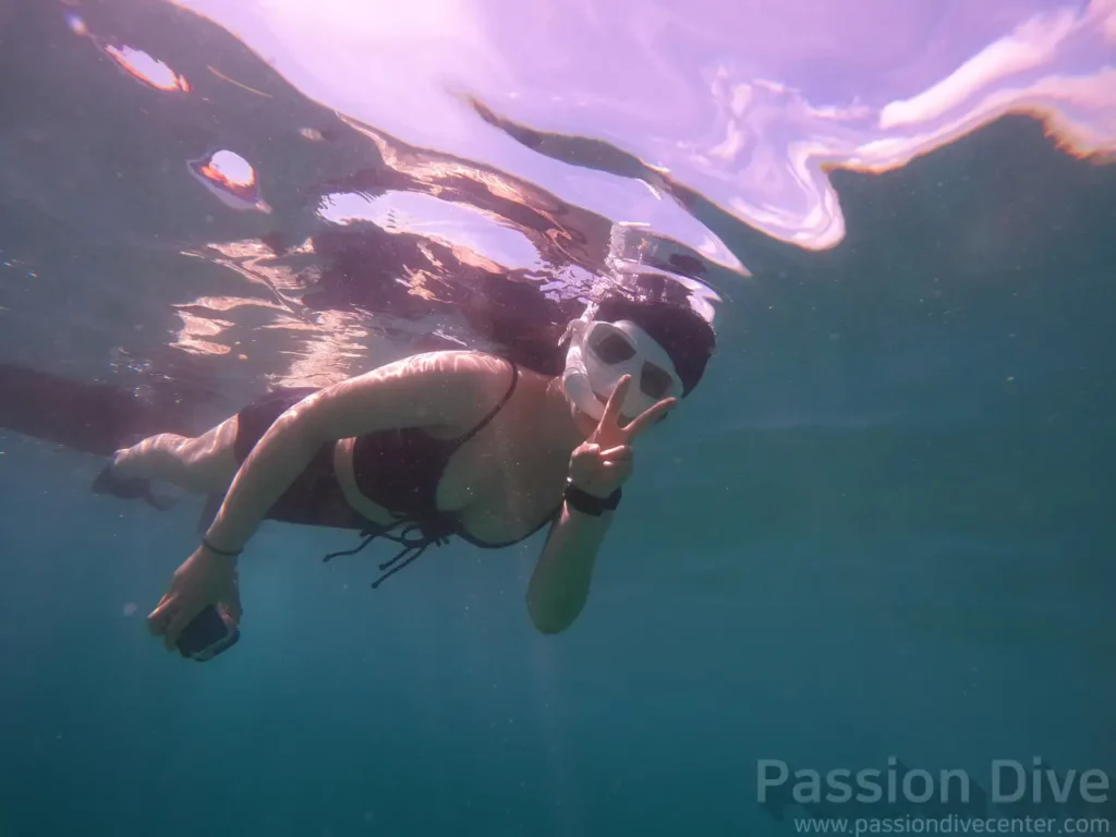 A freediver making a peace sign just below the surface at the Passion Dive housereef in Cebu
