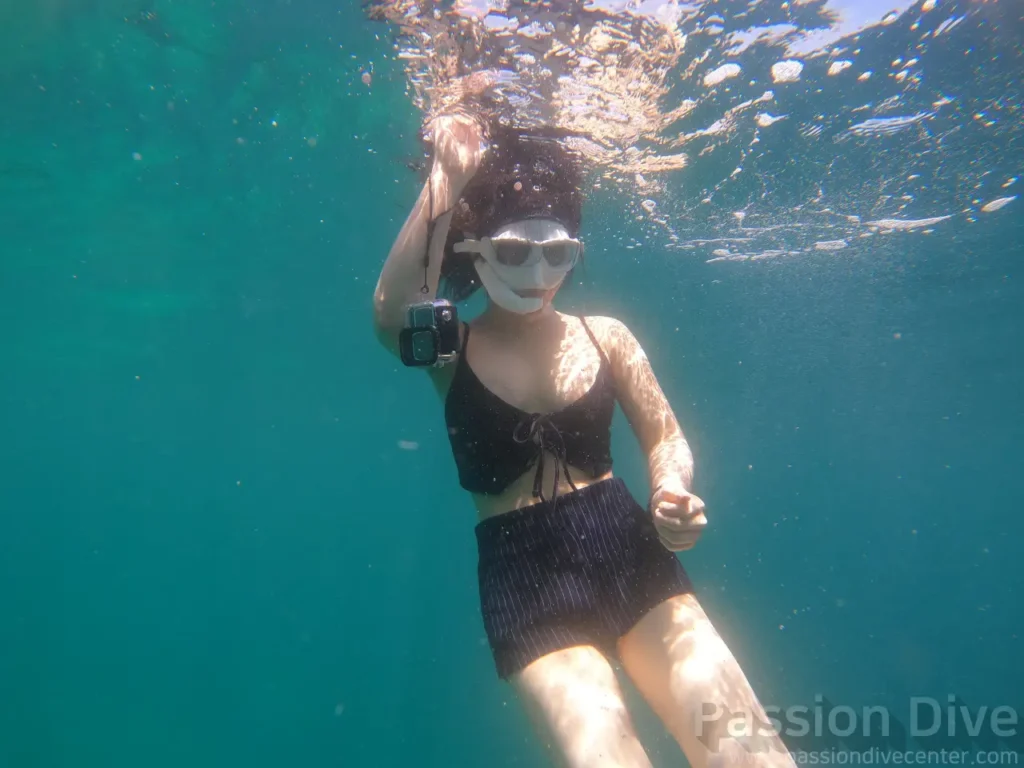 A freediver swimming underwater while filming with a GoPro at the Passion Dive housereef in Mactan, Cebu